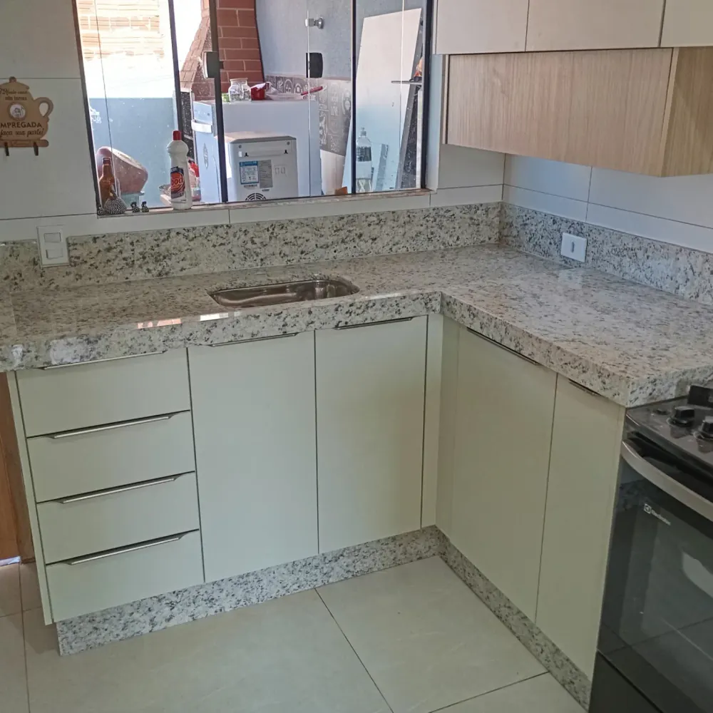 Cozinha em L com bancada em granito claro pontilhado e cuba embutida