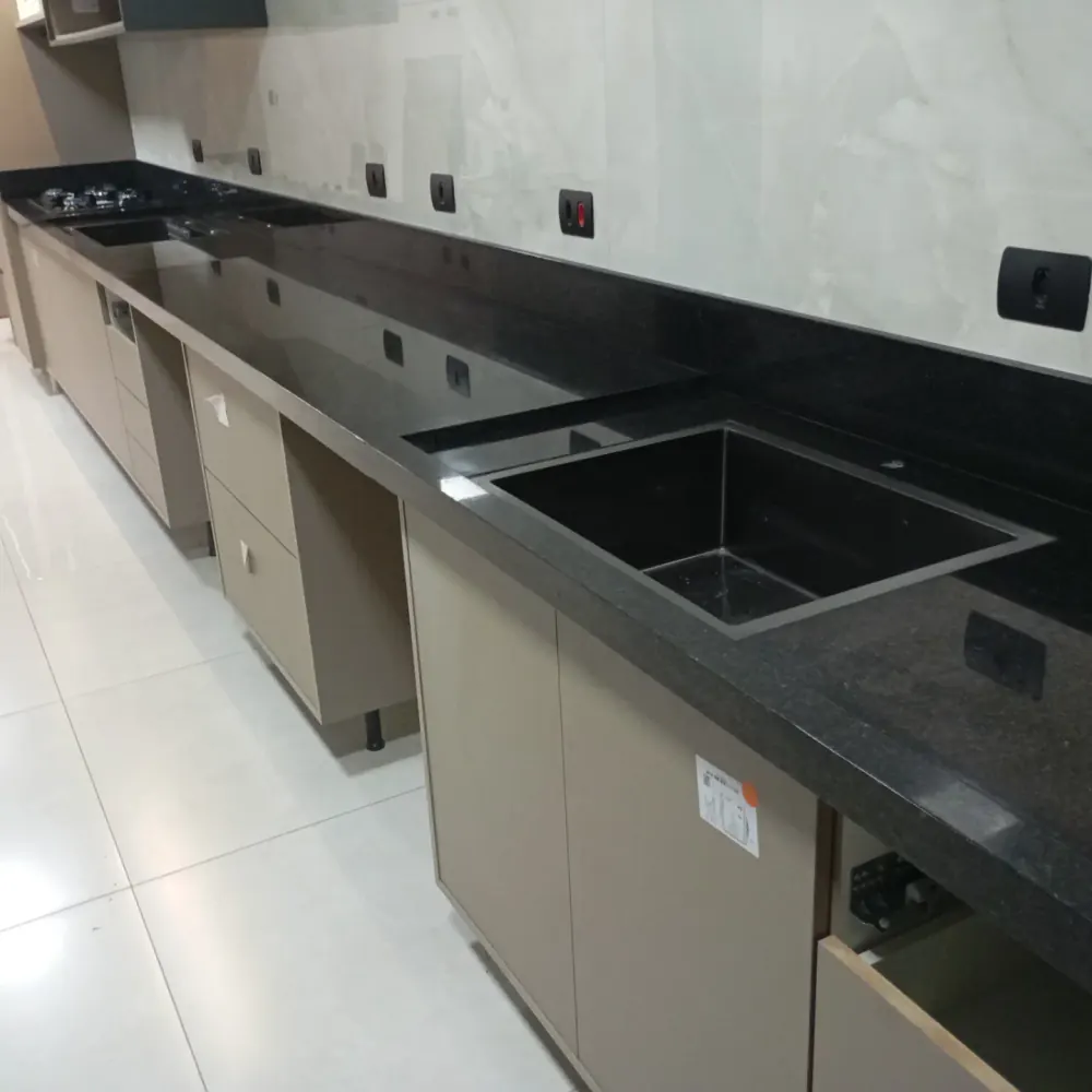 Bancada linear em granito preto com cuba embutida e armários claros