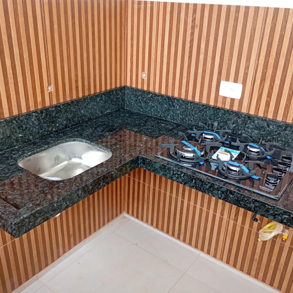 Bancada em granito verde com cooktop, ao lado de parede ripada de madeira