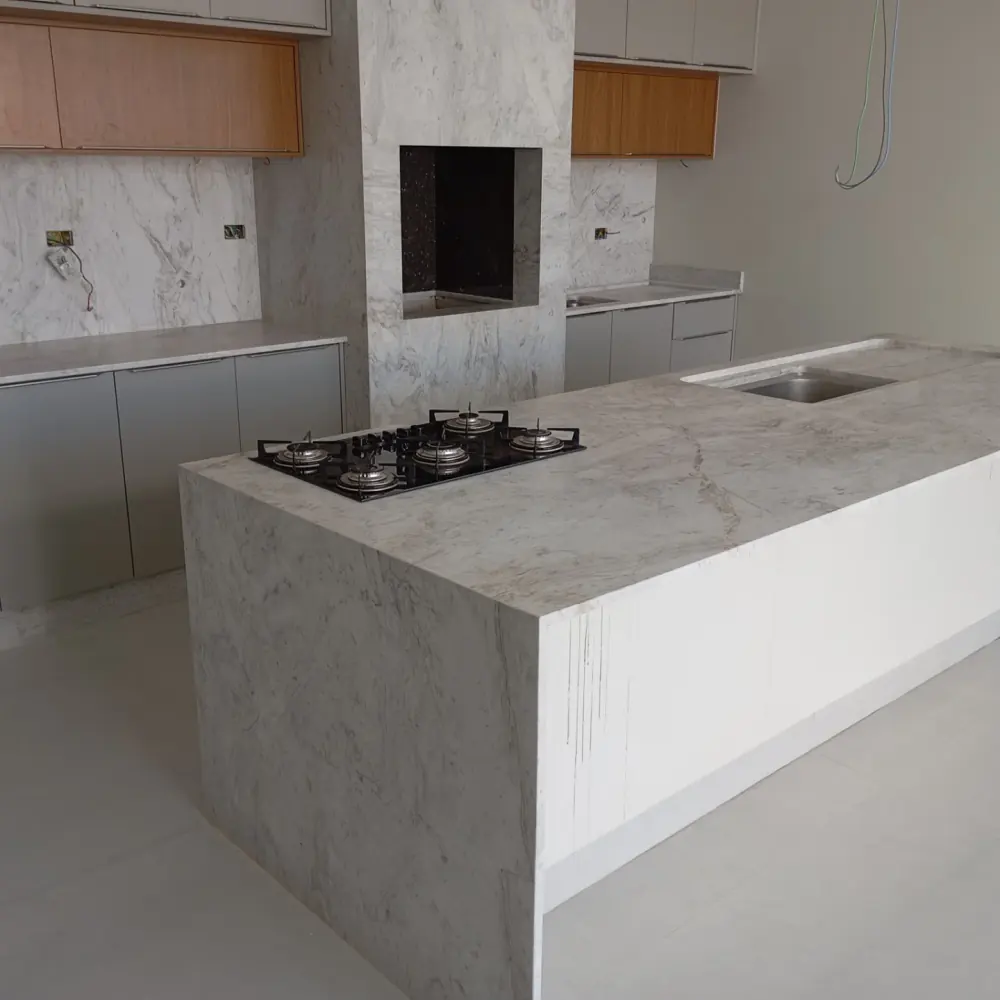 Ilha em mármore branco com cooktop, ao lado de churrasqueira revestida