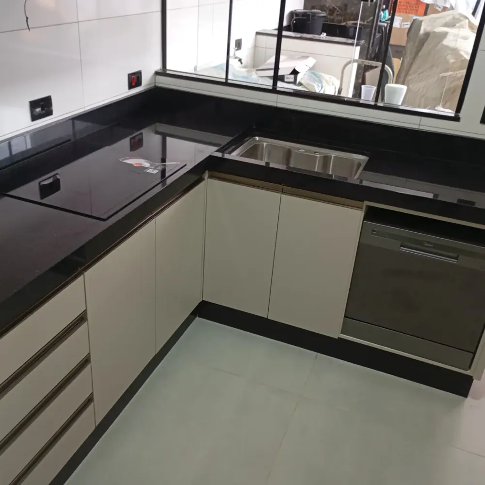 Cozinha em L com bancada em granito preto e cuba de inox